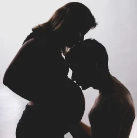 Photo d'une femme enceinte avec son compagnon qui embrasse son ventre