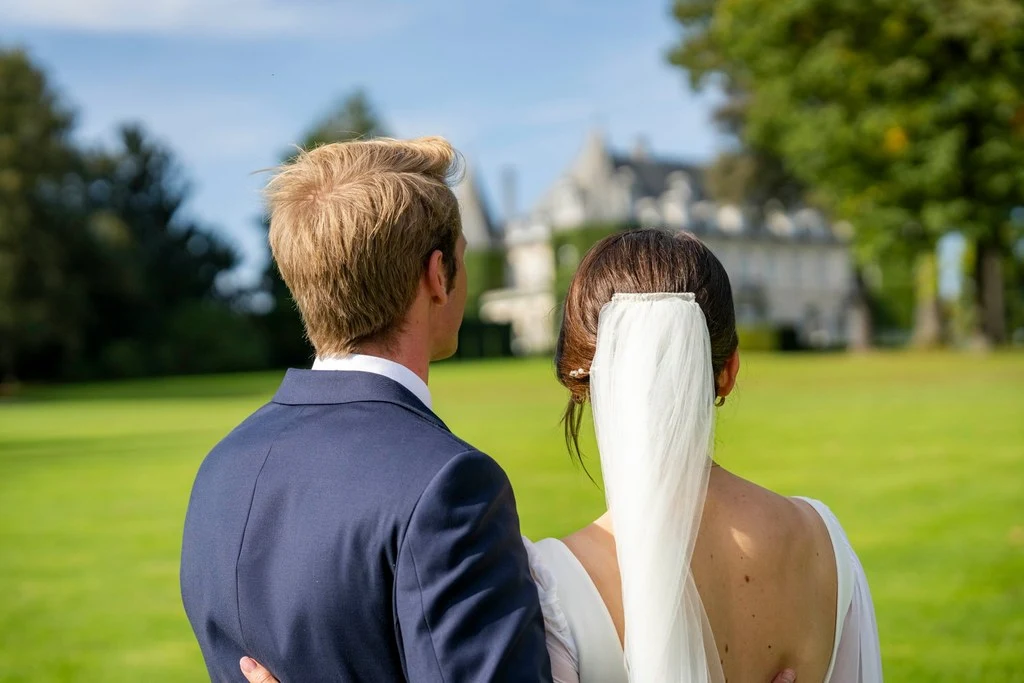 Photo de deux jeunes mariés de dos face à un château
