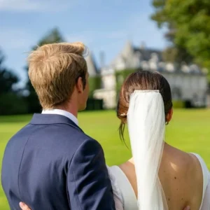 Photo de deux jeunes mariés de dos face à un château