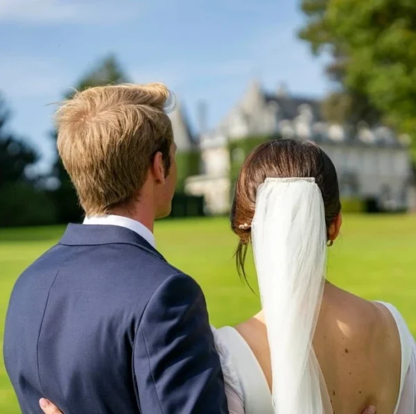 Photo de deux jeunes mariés de dos face à un château