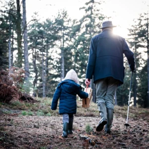 Photo d'un papy et sa petite fille de dos se baladant dans la forêt