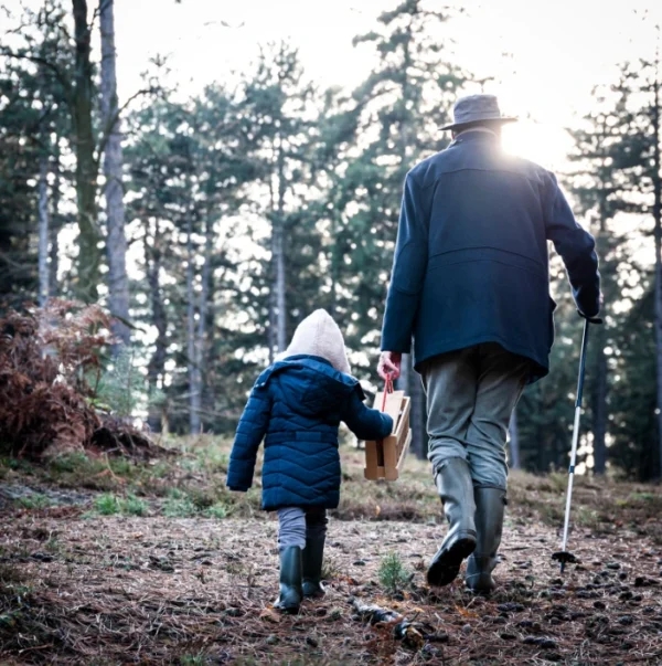 Photo d'un papy et sa petite fille de dos se baladant dans la forêt
