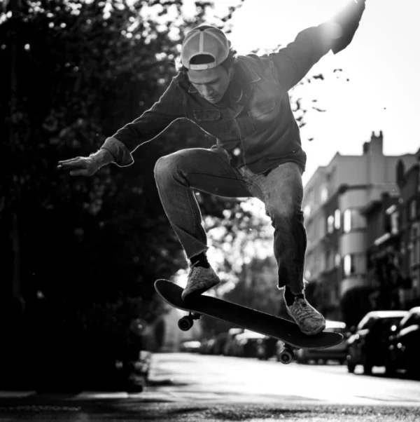 Photo d'un skateur en noir et blanc faisant une figure dans la rue